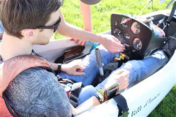 Un futur pilote est installé dans un planeur et un instructeur lui explique le tableau de bord.